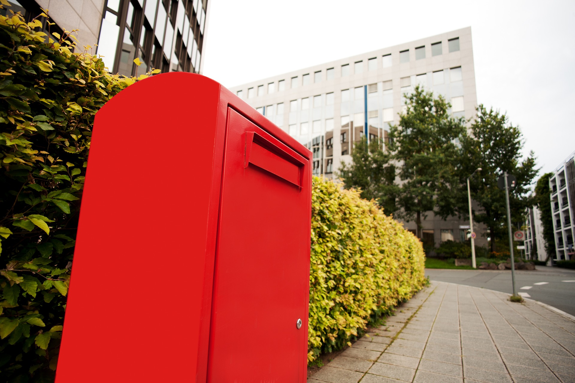 Roter Briefkasten vor einer Hecke