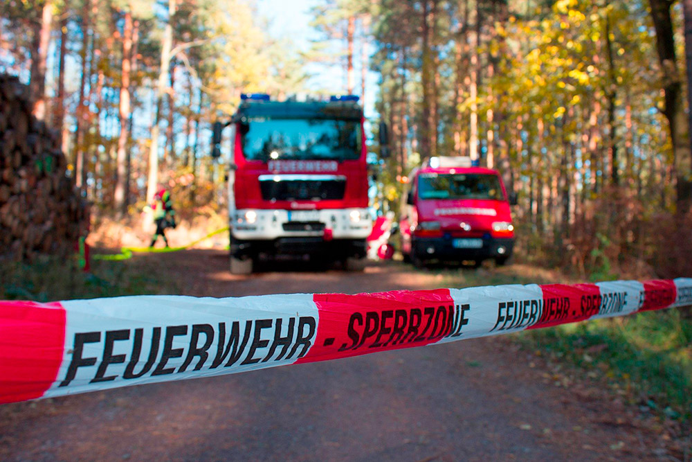Feuerwehr-Fahrzeuge hinter Sperrband im Wald