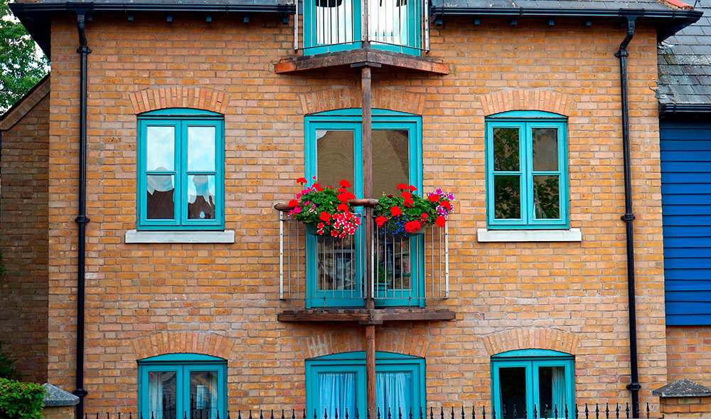 Haus mit Miewohnungen, hier rotes Backsteinhaus mit blauen Fensterrahmen.